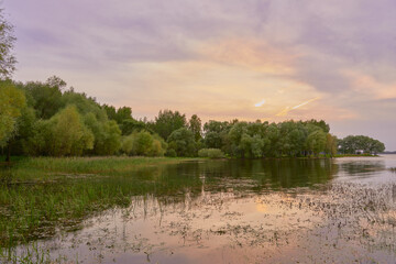 Early autumn landscape. Sunset over a grassy lake.
