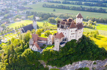 View from drone of stone Gutenberg Castle on top of green hill on background with small town of Balzers, Liechtenstein