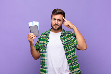 young man feeling confused and puzzled, showing you are insane, crazy or out of your mind. holidays...