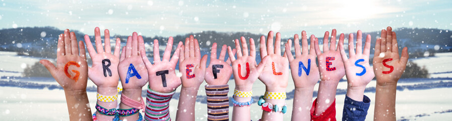 Children Hands Building Colorful English Word Gratefulness. Snowy Winter Background With Snowflakes