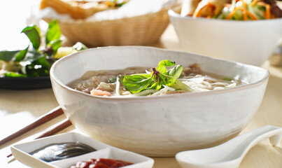 vietnamamese meal with beef pho bo soup accompanied by hoisin sauce and sriracha