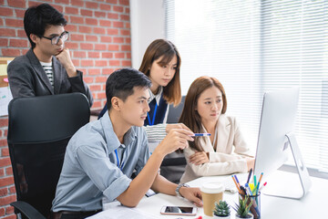 Creative business Asian colleagues discussing over computer in office.