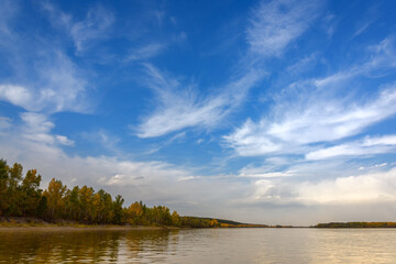 Fototapeta premium landscape on the river, blue sky with clouds, Bank edge with autumn forest