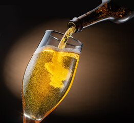 Jet of beer out of the bottle is poured into a beer glass, causing a lot of bubbles and foam.