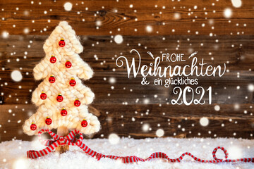 German Calligraphy Frohe Weihnachten Und Ein Glueckliches 2021 Means Merry Christmas And A Happy 2021. White Fabric Christmas Tree With Red Ball Ornament. Wooden Background With Snow And Snowflakes