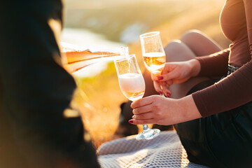 A photo of girls hands holding two glasses of champagne at picnic