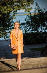 Fashionable woman in orange trench. Woman in coat at street, woman outfit. Fancy style for ladies, autumn colors and fashion details 