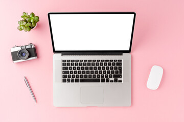 Modern laptop with empty screen on pink background with accessories. Office desktop concept. Top view