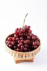 Red seedless grapes in bamboo basket on white background