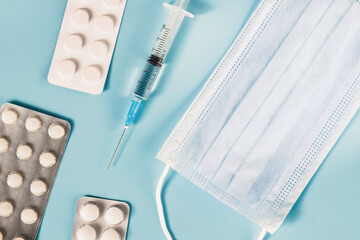 Medical preparations. Medical mask, medicine, tablets, injection syringe on a blue background.
