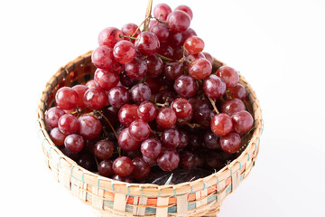 Red seedless grapes in bamboo basket on white background