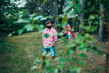 Hiking in deep wood. Mature man with beard in hat. Human and nature. Masculinity and brutality concept.Hipster tourist explore forest.