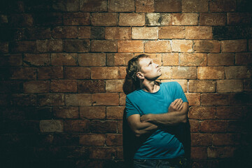 Front view man under life crisis problems standing back propping up brown brick wall looking up...