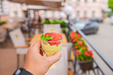 Layered dessert with fruit and cream cheese in glass jar, selective focus. Strawberry milk dessert in a small glass.