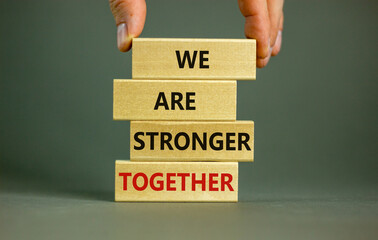 Male hand placing a block with word 'we' on top of a blocks tower with words 'we are stronger...