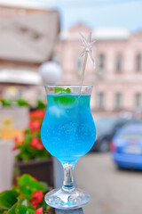 Blue curacao cocktail in a tall glass with a plastic straw outside. Delicious dessert drink, refreshing summer beverage.
