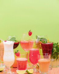 Summer drinks with fruit juice and ice. Refreshing summer beverages in different glasses over green background.