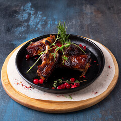 Juicy grilled pork ribs with barbeque sauce on a frying pan.