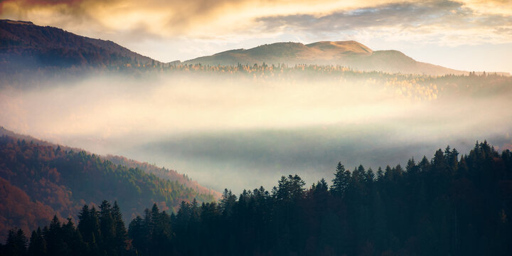mountain landscape in autumn. fog glowing in morning light. dramatic sky with clouds at sunrise