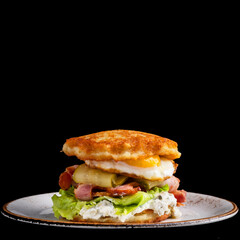 Delicious potato pancakes burger with fried eggs, bacon and salt cucumber on a black background. Traditional food. Draniki. Copy space
