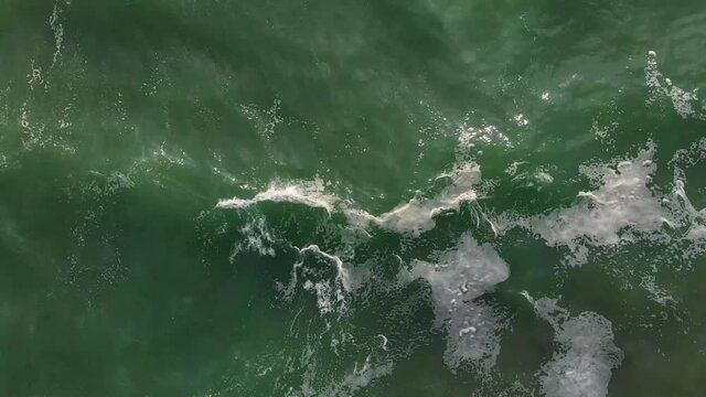 Aerial drone footage of sea waves from ocean to beach, brown sand and emerald water color are contrasted. Beautiful nature footage is 4K 30fps.