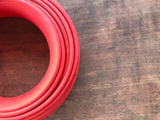 The red solar cable cord roll on a dark brown wooden table.
