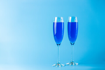 Two wineglasses close up of blue champagne on a blue background. Shallow depth of the field, copy space for you text
