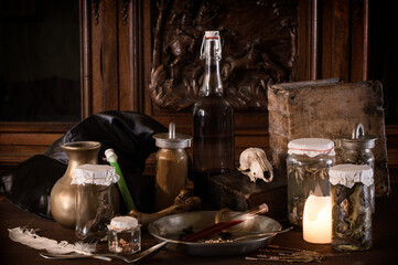 Fototapeta na wymiar eerie witches' kitchen with lot of ingredients for a potion and ancient gruesome jars dark with only candlelight for Halloween
