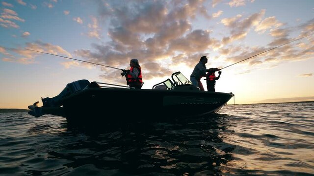 Children are catching fish with their father while being on a boat