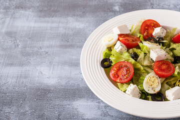 Fresh vegetables salad with tomatoes, quail eggs, lettuce,  cheese and black olives. Healthy and diet food concept. Copy space