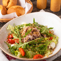 Meat salad with arugula, quail eggs, tomatoes and walnuts.