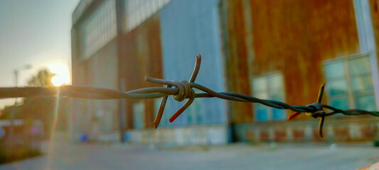 Barbed wire of a closed aircraft hangar at sunset