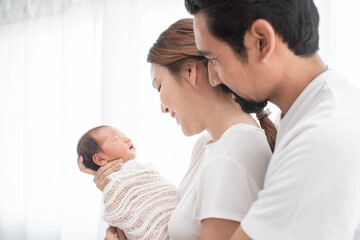 smiling mother and father holding their newborn baby at home..portrait of happy family at home, young parents holding on hands little sweet newborn baby, love and happiness concept.