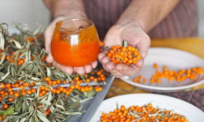 Vitamin healthy sea buckthorn tea in a glass cup with a teapot, honey, jam, fresh raw sea buckthorn...