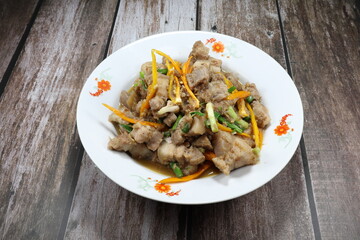 Traditional fried and stirred chopped pork belly with chilly and spring onion seasoning with local sauce on the plate. Famous hot and spicy menu in Asia restaurant. 