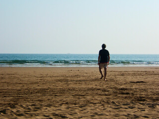 a man walks towards the sea on Agadir beach, Morocco