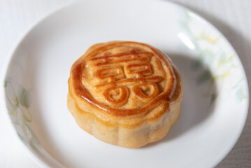 Chinese traditional food , pie with chinese character for happiness , betrothal gift , mooncake on plate