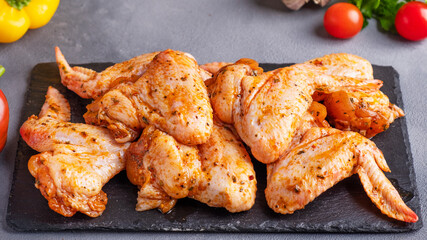 Marinated chicken wings on black stone background.