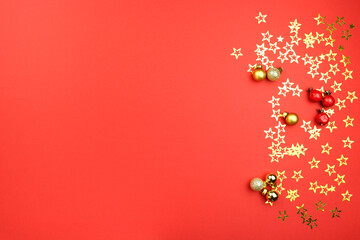 Fototapeta na wymiar christmas composition on red background with golden stars, balls, berries. Concept holiday atmosphere, new year, celebration, greeting card. Flatlay, top view, copyspace