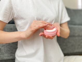 Close-up of a woman's hands holding a jar of face cream. Shallow depth of field with an emphasis on moisturizer.