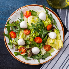 Top view of healthy and diet salad. Fresh salad with arugula, lettuce,  cherry tomatoes and mozzarella cheese.