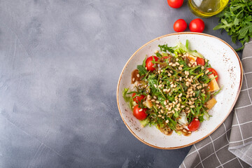 Top view of diet arugula salad with fresh tomatoes, cheese and pine nuts. Text space