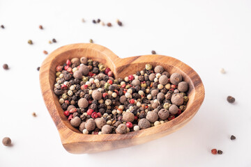 Mixed of peppers in a wooden bowl.  Hot, red, black, white and green pepper isolated on white.