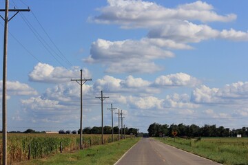 power lines in the countryside with a blue sky,clouds, and a highway north of Hutchinson Kansas USA...