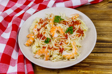 Spaghetti pasta with prawns, tomato sauce and parsley on wooden table