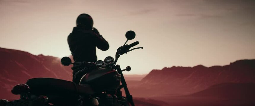 Biker enjoying a scenic view of a sunset over mountains during motorcycle ride