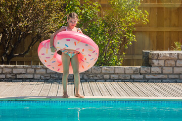 cute young girl playing in the pool with her inflatable donut