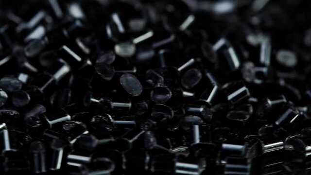 Close-up rotation of black plastic polymer granules on black background