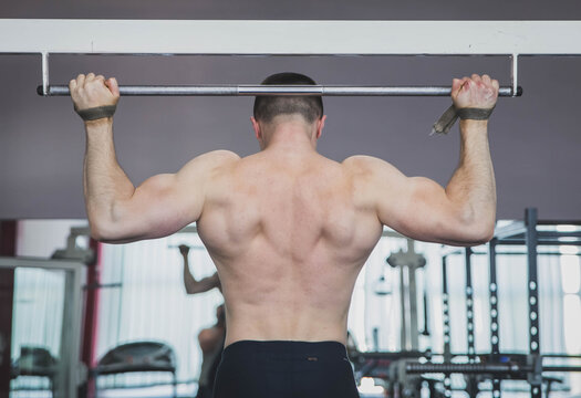 athlete pulls up in the gym fastening hands on the horizontal bar