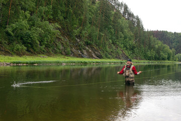 Fototapeta na wymiar Fly fishing. Fisherman alone stand in river water. Hobby sport activity